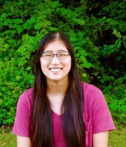 Author photo. Asian, twenties, glasses, red shirt. The background is green leaves.